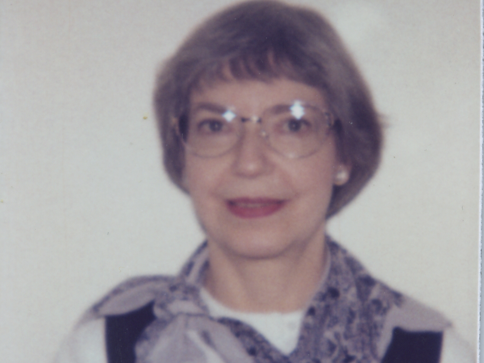 An old photograp, slightly out of focuss of Lila Levy, who is wearing glasses with a short haircut and a dark blouse with white sleeves and a blue scarf.